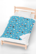Patterned childrens velveteen blanket with chicken, cat, and little girl cartoon characters and flowers on a blue background